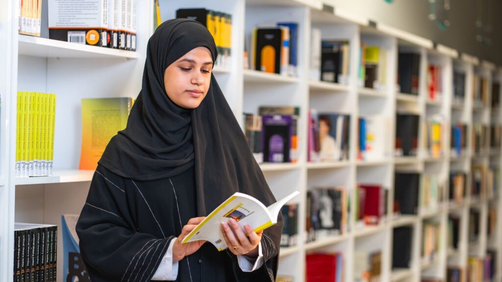 Une jeune étudiante lisant un livre dans une bibliothèque universitaire